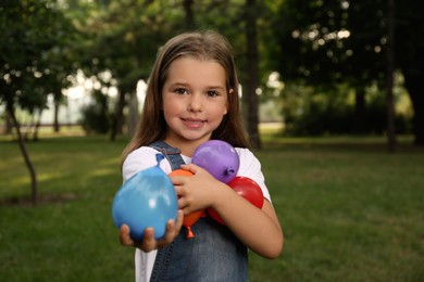 Cute little girl holding water bombs in park