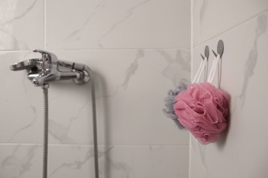 Shower puffs hanging near faucet in bathroom, space for text