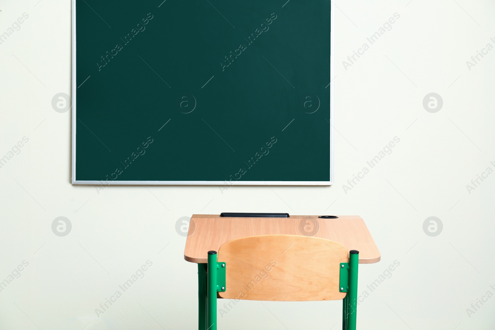 Photo of Modern empty school desk near chalkboard in classroom