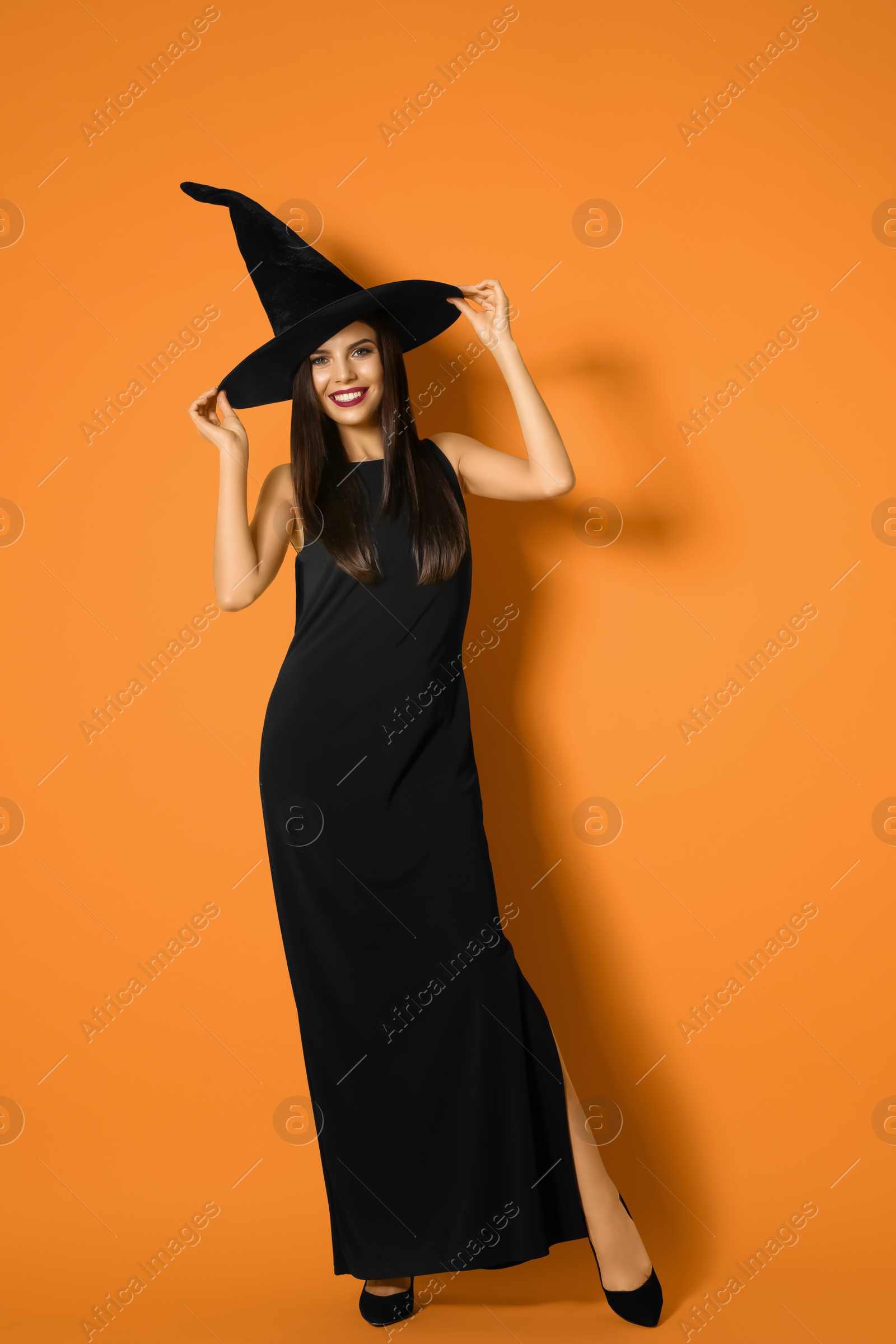 Photo of Beautiful woman wearing witch costume for Halloween party on yellow background