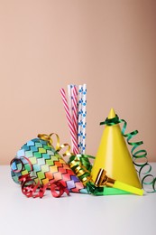 Photo of Colorful party hats, streamers and straws on white table. Birthday celebration
