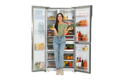 Photo of Young woman with broccoli and avocado near open refrigerator on white background