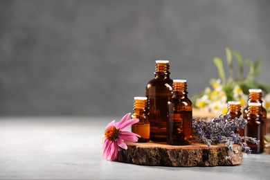 Bottles with essential oils and flowers on light table. Space for text