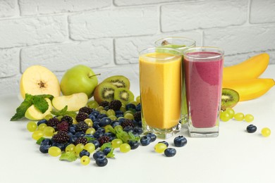Photo of Fresh colorful fruit smoothies and ingredients on white table