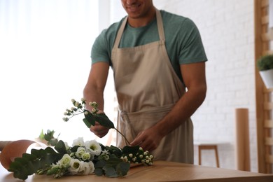 Photo of Florist making beautiful bouquet at table in workshop, closeup
