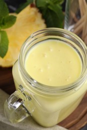 Photo of Tasty pineapple smoothie on wooden board, closeup