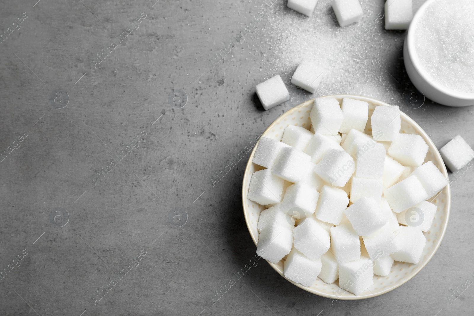 Photo of Refined sugar cubes on grey table, flat lay. Space for text