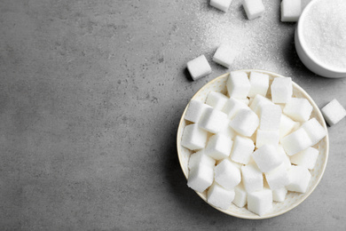 Photo of Refined sugar cubes on grey table, flat lay. Space for text