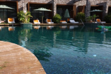 Blurred view of swimming pool, umbrellas and sunbeds at luxury resort