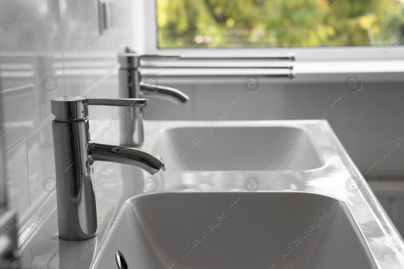 Photo of White clean sinks with water taps in bathroom, closeup