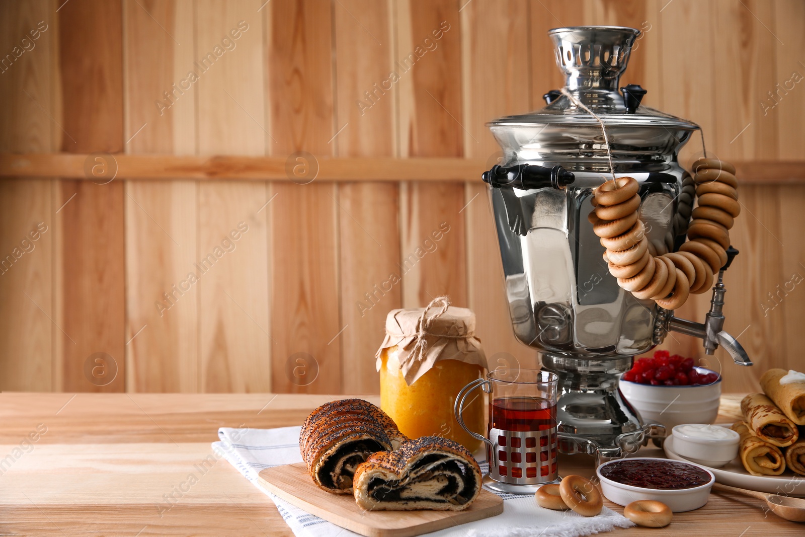 Photo of Traditional Russian samovar and treats on wooden table. Space for text