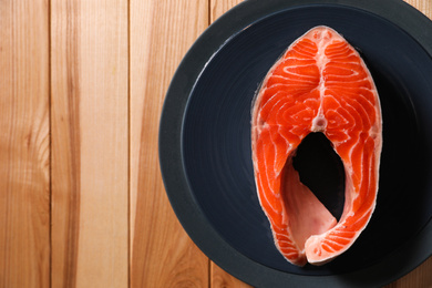 Fresh raw fish steak on wooden table, top view