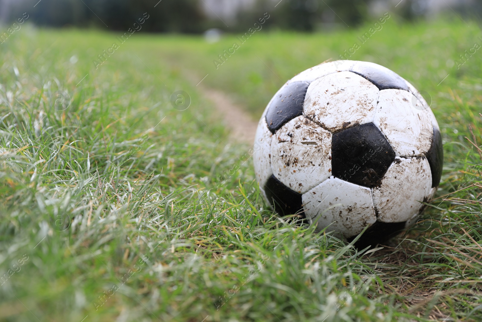 Photo of Dirty soccer ball on green grass outdoors, space for text