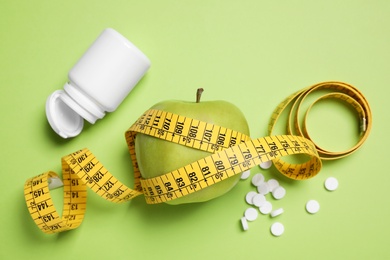 Photo of Flat lay composition with apple and measuring tape on green background. Weight loss