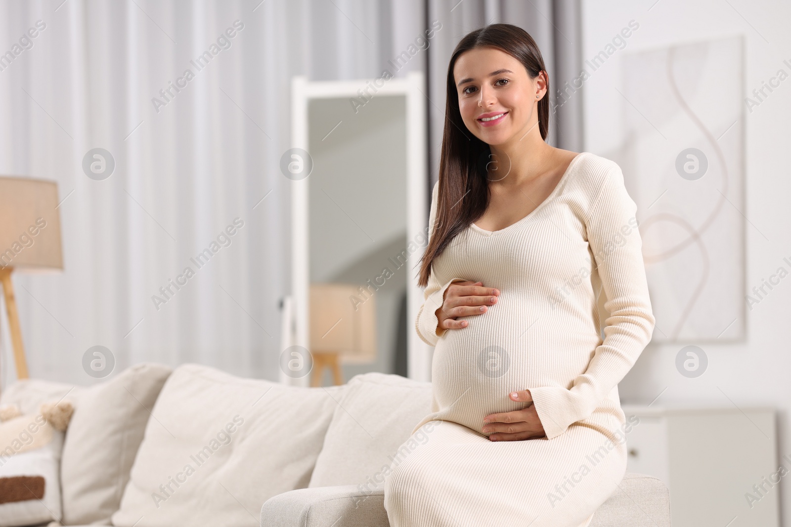 Photo of Beautiful pregnant woman sitting on sofa at home