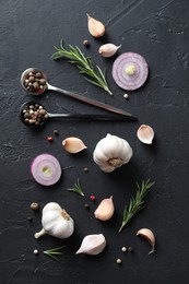 Photo of Fresh raw garlic, onion rings and spices on black table, flat lay