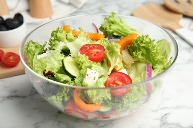 Photo of Tasty fresh Greek salad on white marble table, closeup