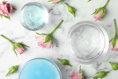 Photo of Flat lay composition with cosmetic gel and beautiful flowers on white marble table