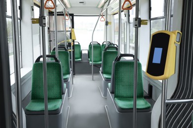 Photo of Public transport interior with comfortable green seats and contactless fare payment devices