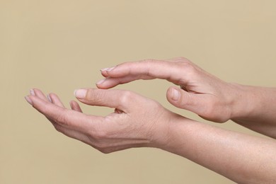 Photo of Closeup of woman's hands with aging skin on beige background. Rejuvenation treatment