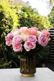 Photo of Vase with beautiful bouquet of roses on light grey table outdoors