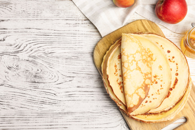 Photo of Flat lay composition with fresh thin pancakes on white wooden table table. Space for text