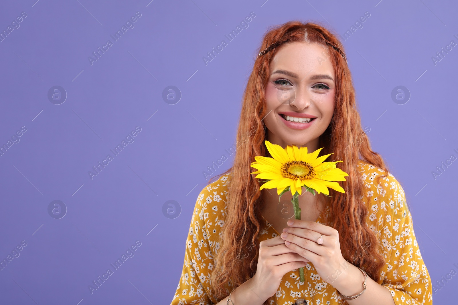 Photo of Beautiful young hippie woman with sunflower on violet background, space for text