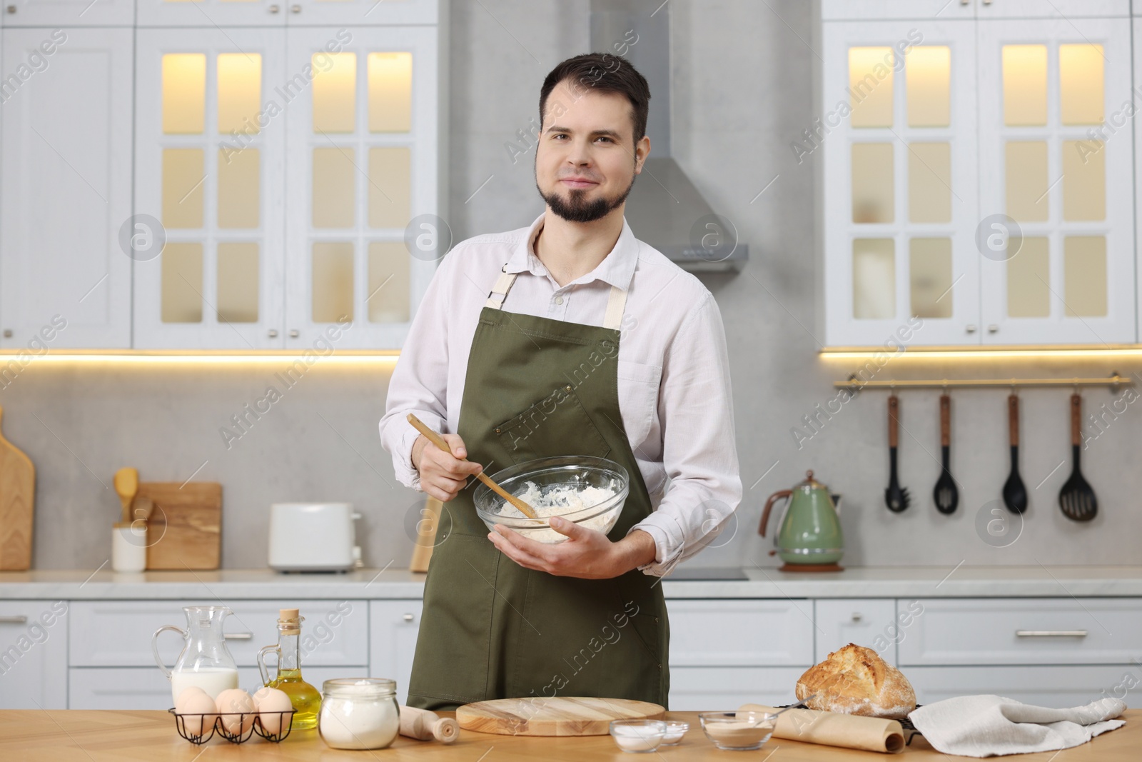 Photo of Making bread. Man preparing dough in bowl at wooden table in kitchen