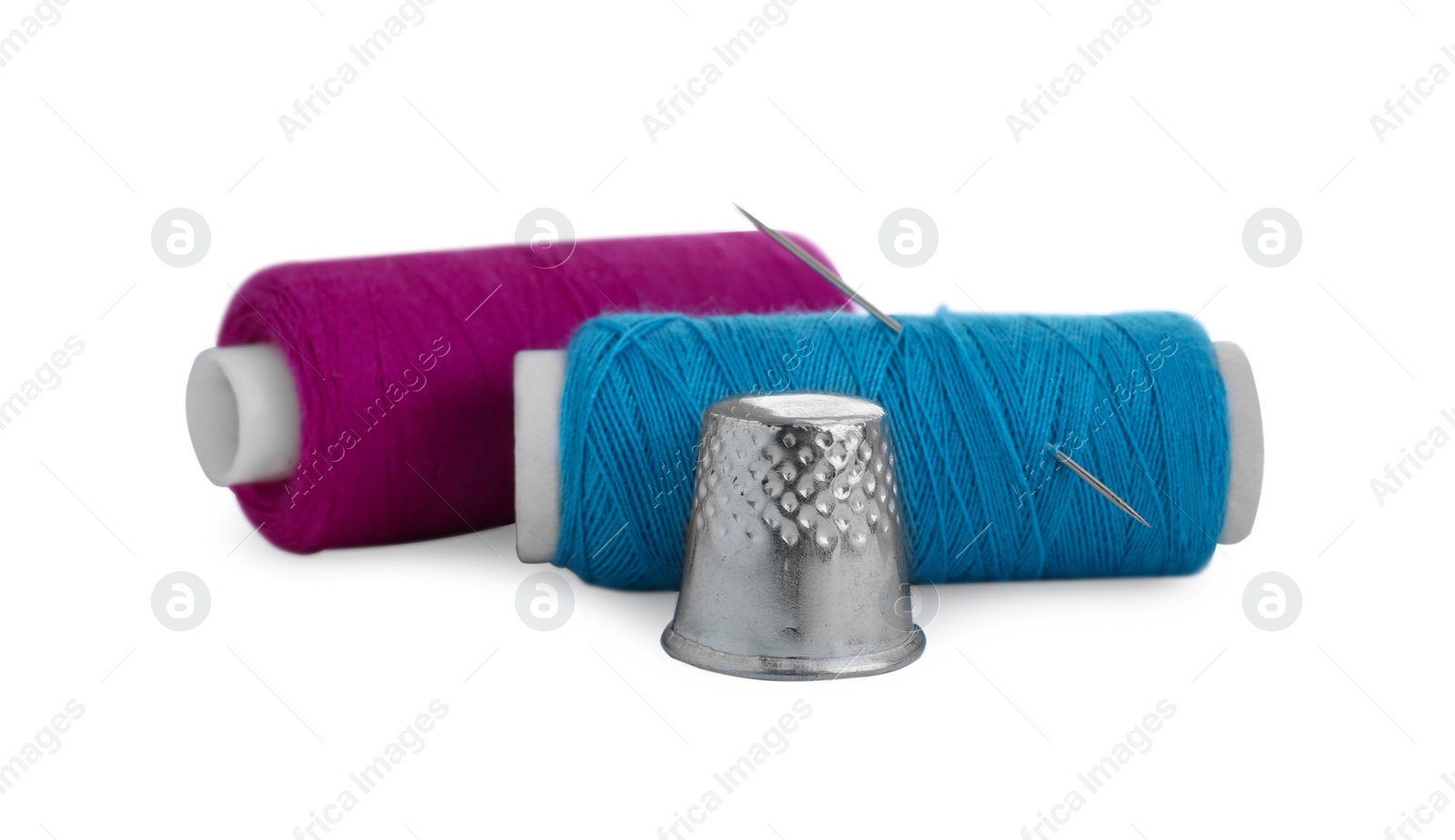 Photo of Thimble, spools of sewing threads and needle isolated on white