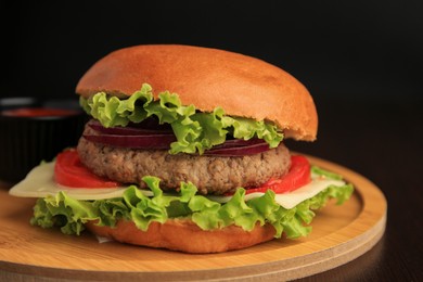 Photo of Tasty burger with vegetables, patty and cheese on wooden table, closeup