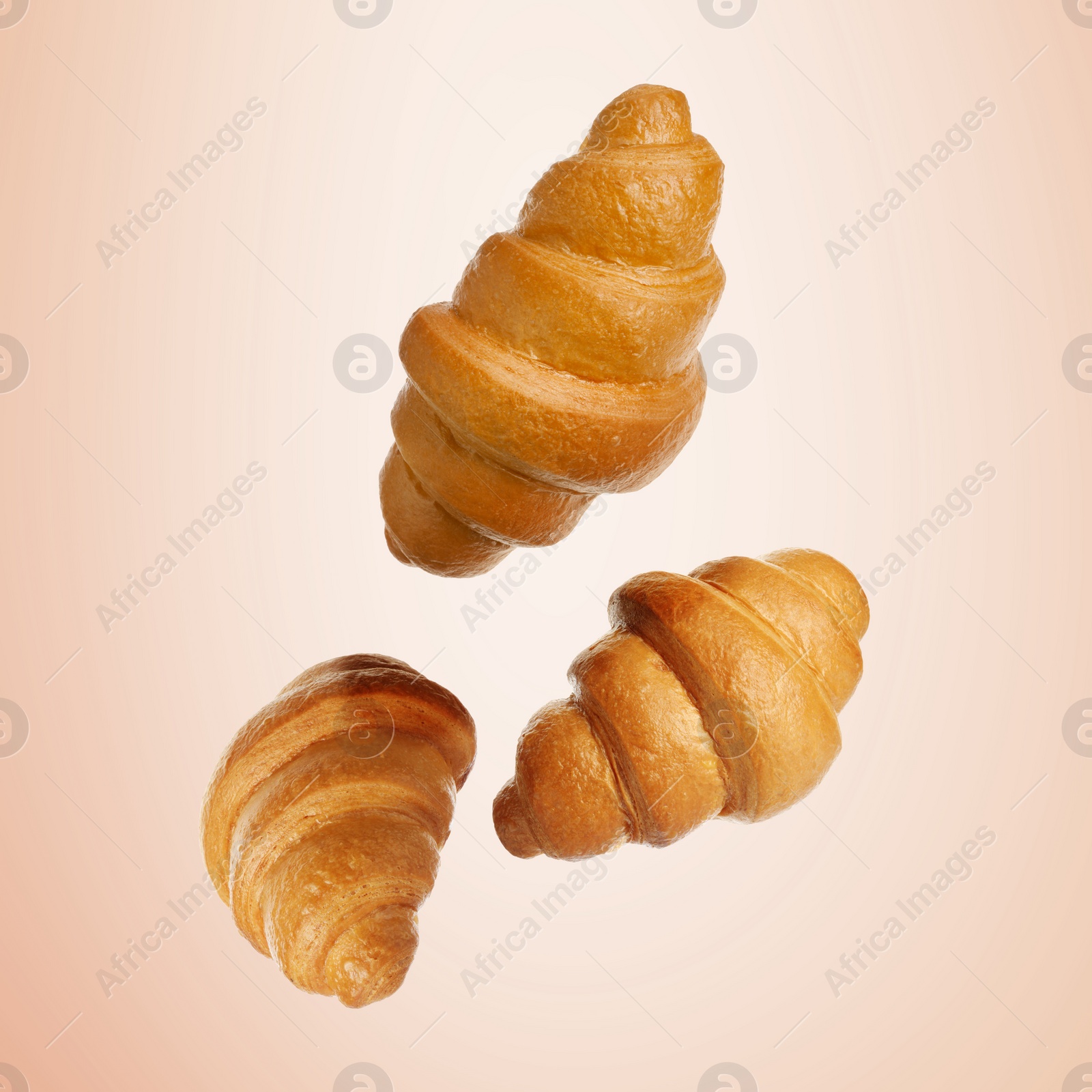 Image of Golden croissants falling on beige gradient background