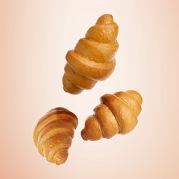 Image of Golden croissants falling on beige gradient background