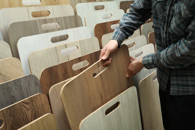 Man choosing wooden flooring among different samples in shop, closeup