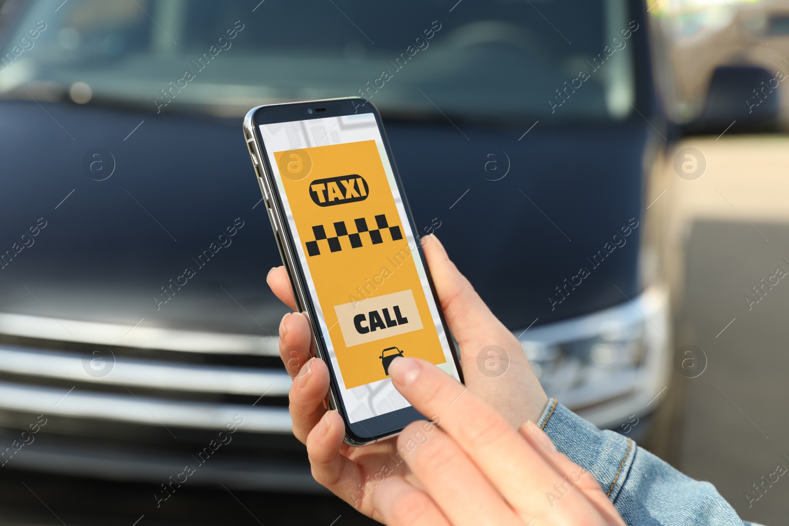 Photo of Woman ordering taxi with smartphone on city street, closeup