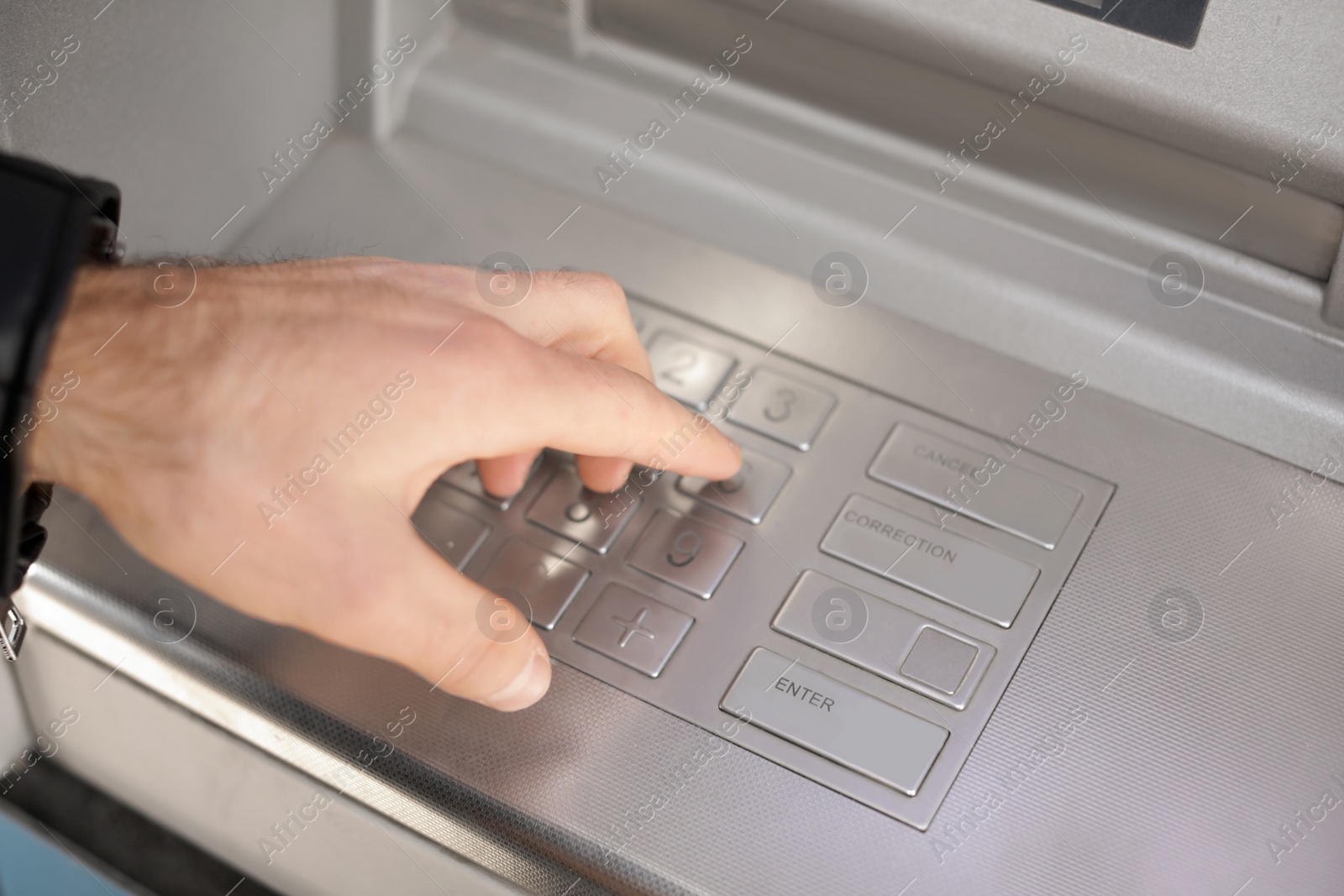 Photo of Man entering PIN code on cash machine keypad outdoors, closeup view