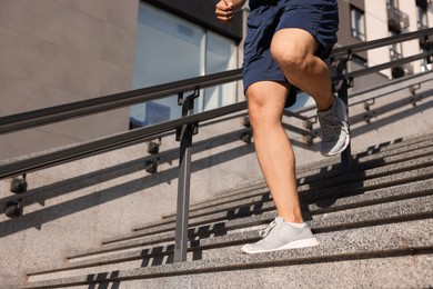 Man running down stairs outdoors on sunny day, closeup. Space for text