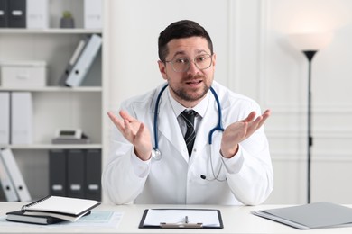 Photo of Emotional doctor working at white table in clinic