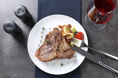 Delicious fried beef meat and vegetables served on grey table, flat lay