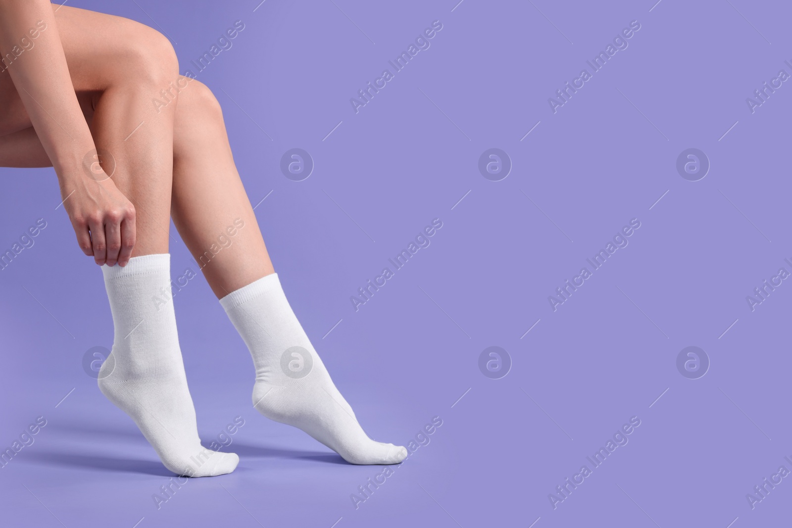 Photo of Woman in stylish white socks on violet background, closeup. Space for text