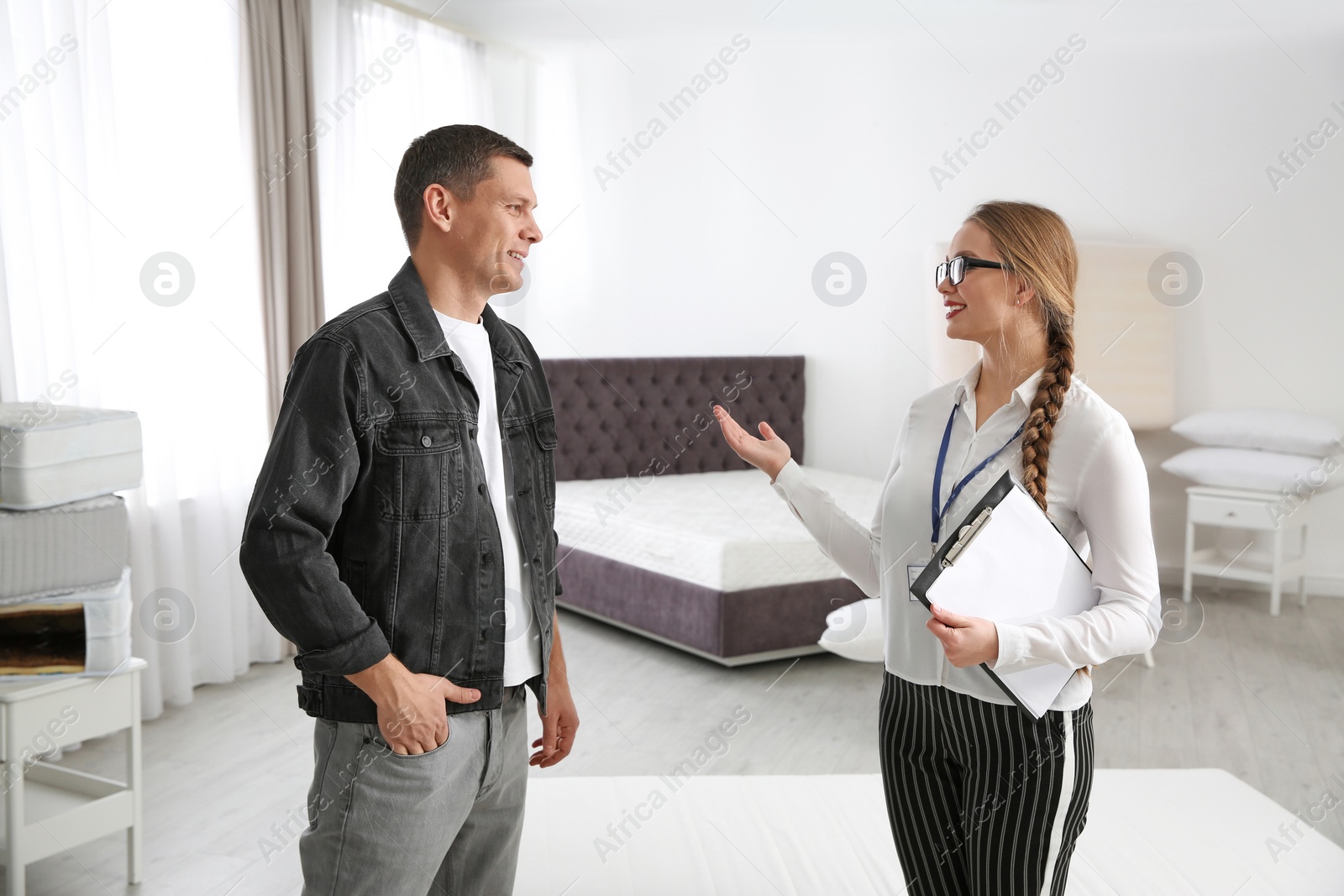 Photo of Young saleswoman consulting man in mattress store