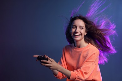 Emotional woman with game controller on dark blue background. Space for text