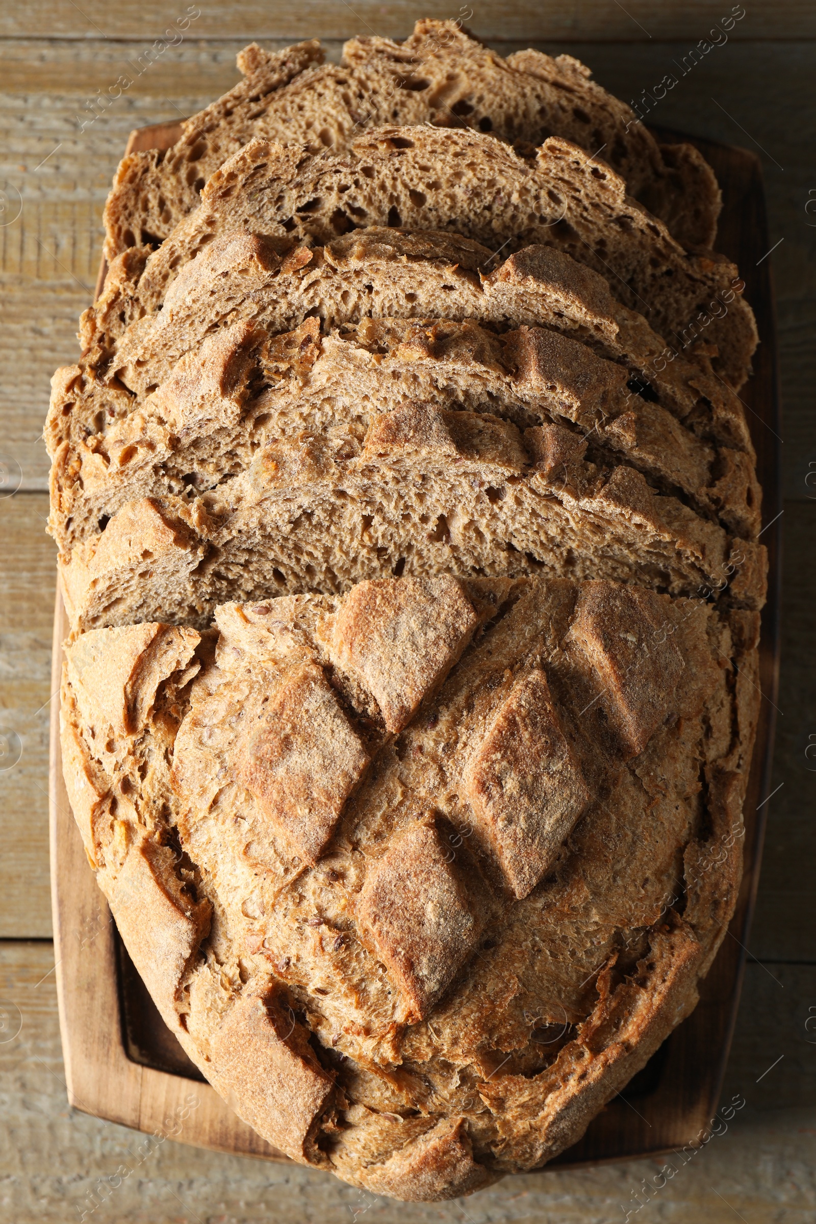 Photo of Freshly baked cut sourdough bread on wooden table, top view