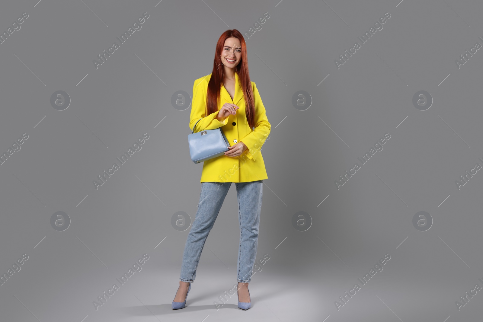 Photo of Stylish woman with red dyed hair and bag on light gray background