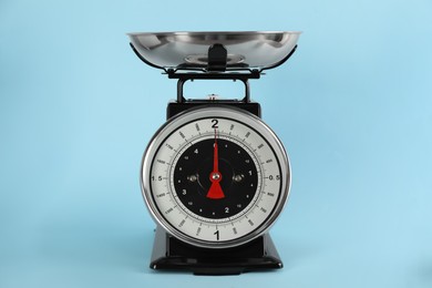 Photo of Retro mechanical kitchen scale on light blue background