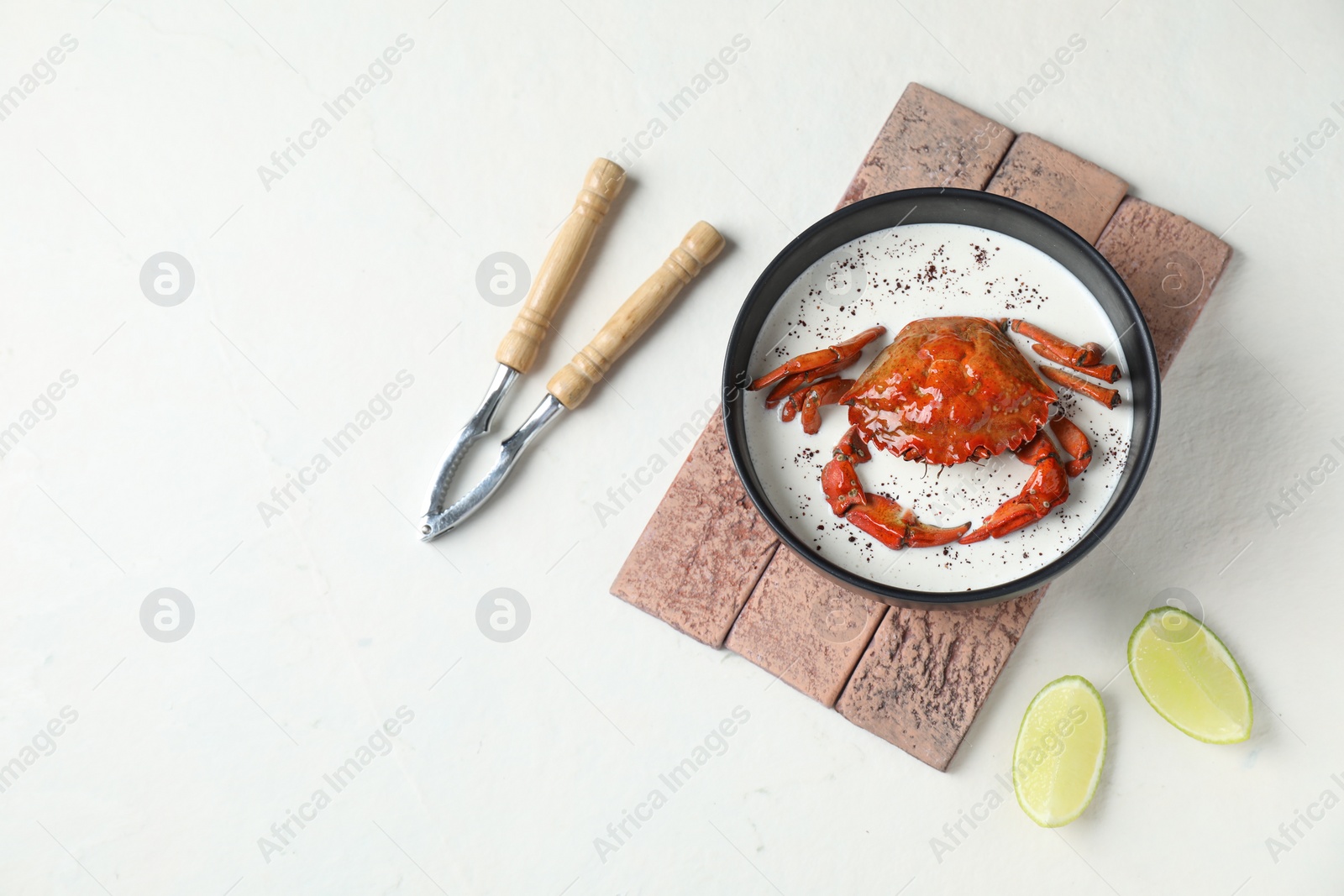 Photo of Delicious boiled crab with cream sauce and lime served on white table, flat lay. Space for text