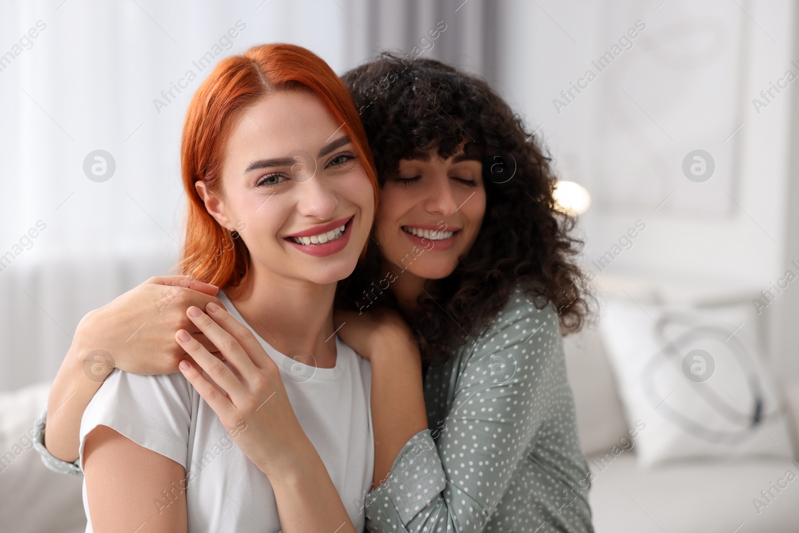 Photo of Portrait of happy young friends hugging at home