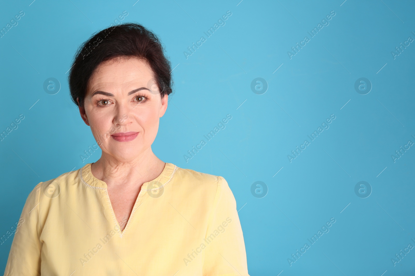 Photo of Portrait of charming mature woman with healthy beautiful face skin and natural makeup on blue background, space for text