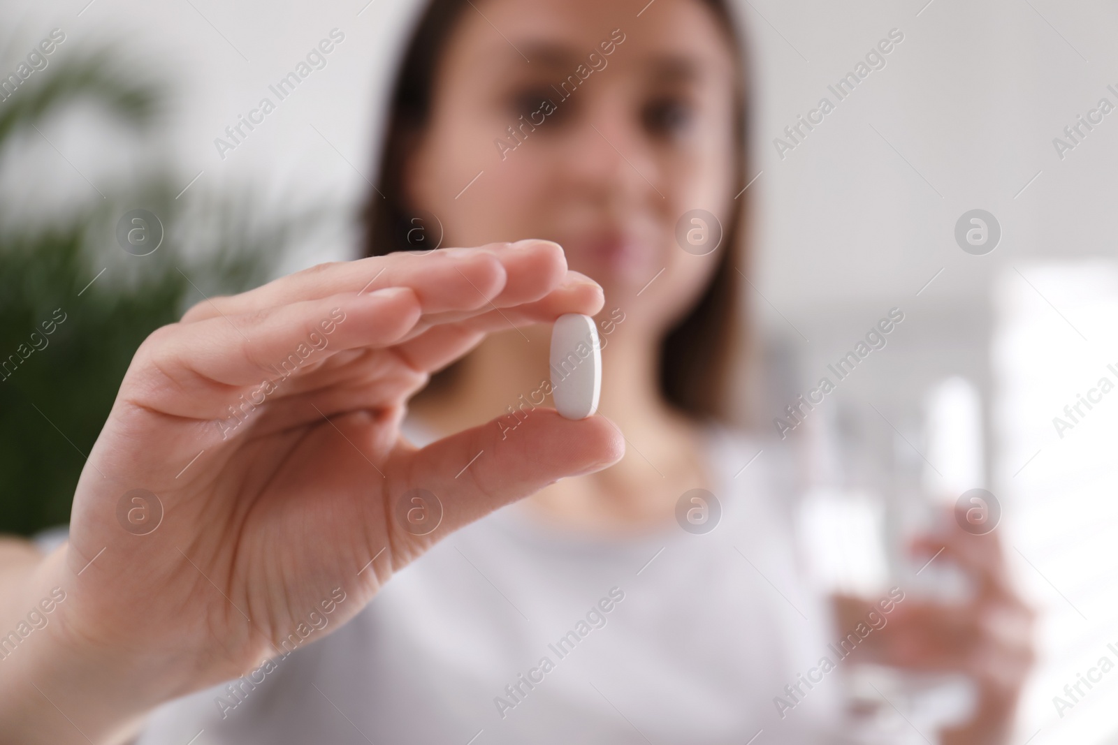 Photo of Woman with pill indoors, focus on hand