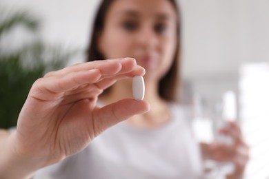 Photo of Woman with pill indoors, focus on hand