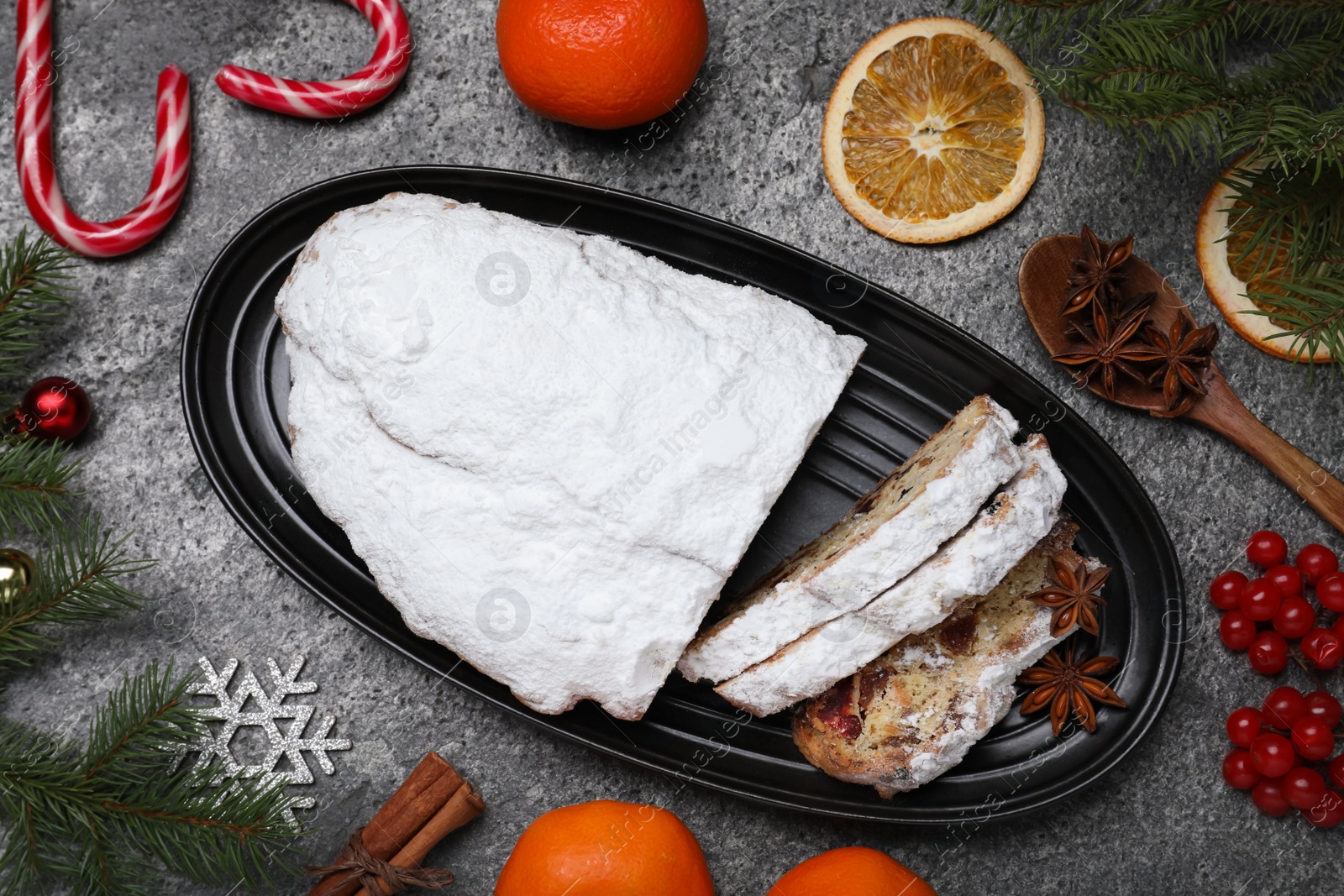 Photo of Traditional Christmas Stollen with icing sugar on grey table, flat lay